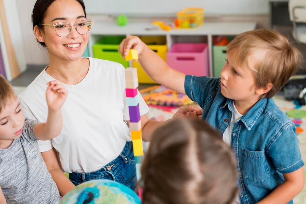 Bambini che giocano in gruppo con la supervisione di un'operatrice